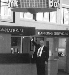 J. Alton Wingate pointing to bank branch sign